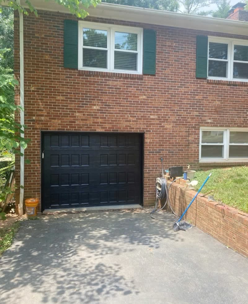 New black raised-panel door installed on a brick home in Davie County